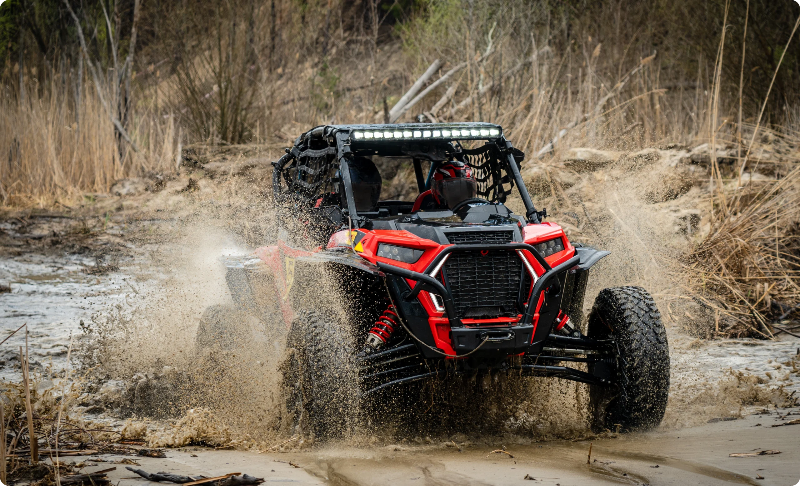 Side-by-side utility vehicle splashing through mud, a power sports application